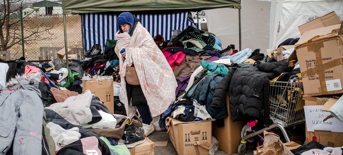Tras de cruzar la frontera con Polonia, una mujer ucraniana busca una manta para que su hijo entre en calor con una manta.
